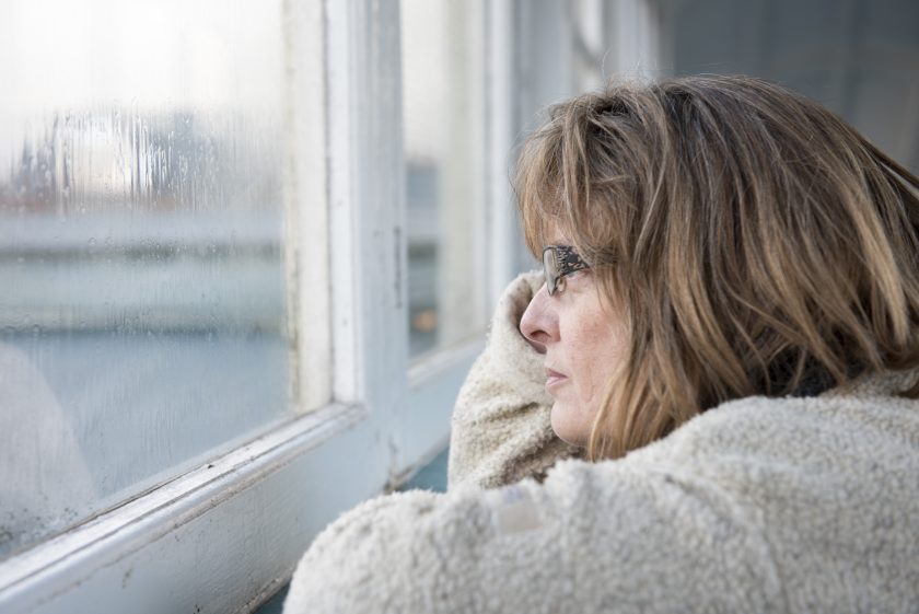 Lady wearing glasses stares out a window